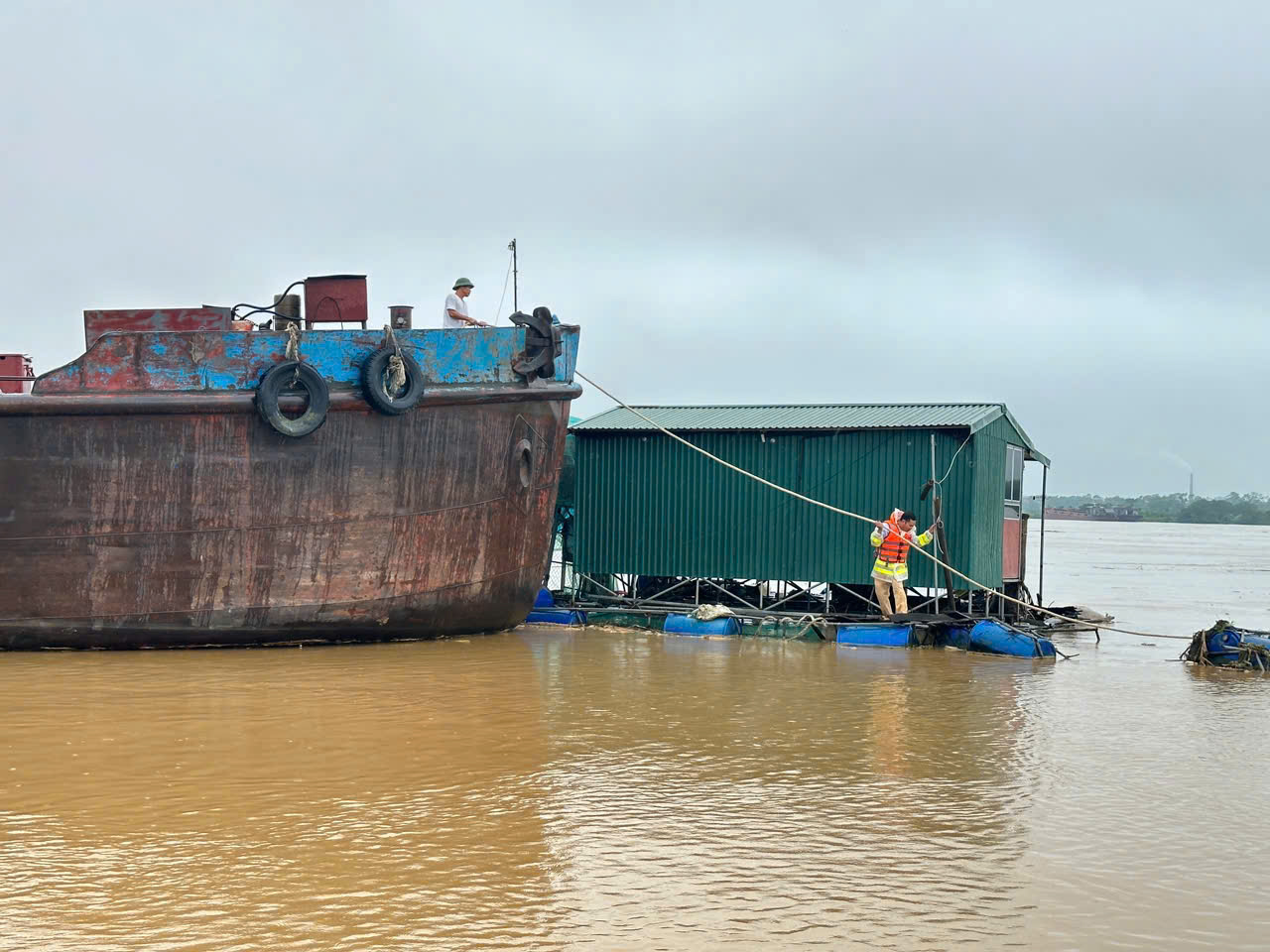 Lực lượng chức năng đã tiếp cận đưa thành công hai nhà nổi và người dân cùng lồng nuôi cá gặp nạn vào bờ cố định an toàn